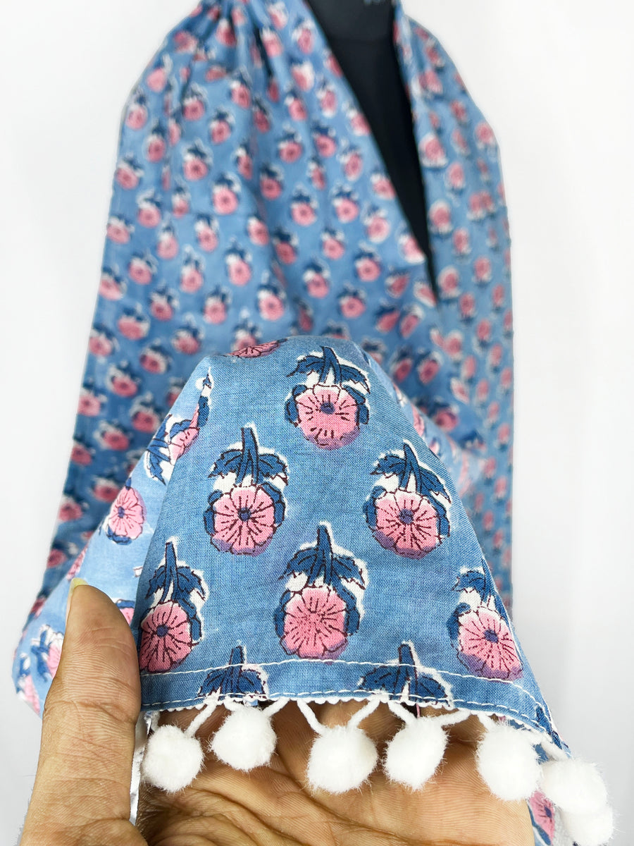 Pom-pom edging and a blue floral print scarf make this accessory lightweight and fashionable